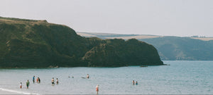 People enjoying a day at Broad Haven beach with cliffs in the background